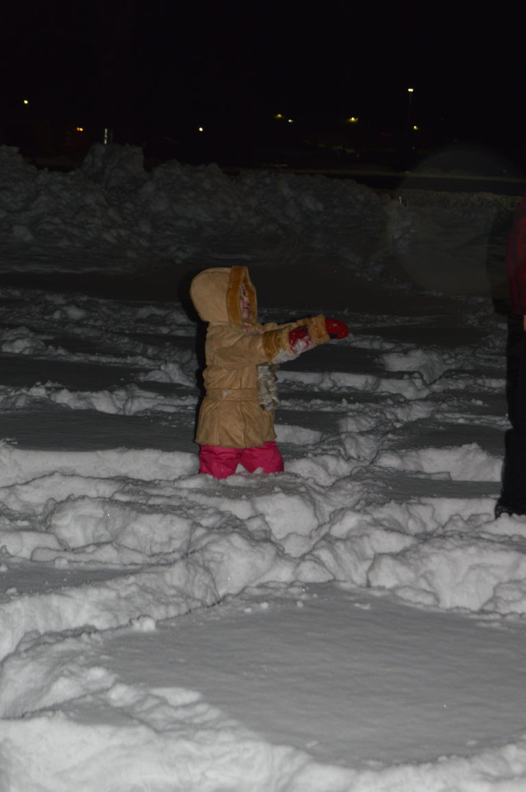 A person standing outdoors in the snow at night
